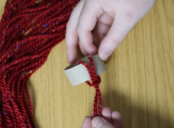 wrapping single pieces of wool around the cardboard tube and pulling them taught